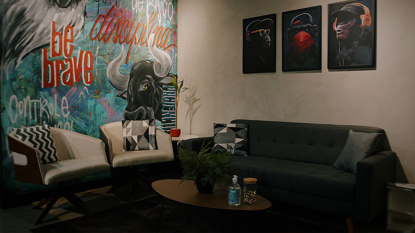 Living do estúdio com sofá, poltronas e arte mural — área de descanso para convidados