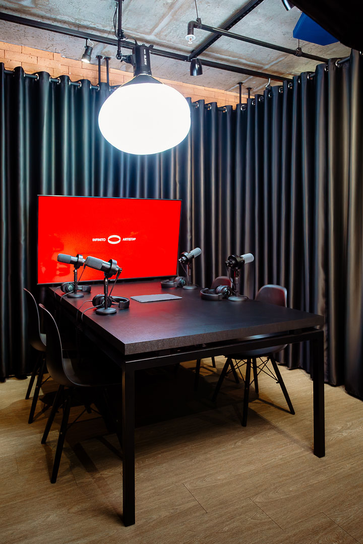 Mesa de gravação com 4 microfones broadcast e TV de cenário