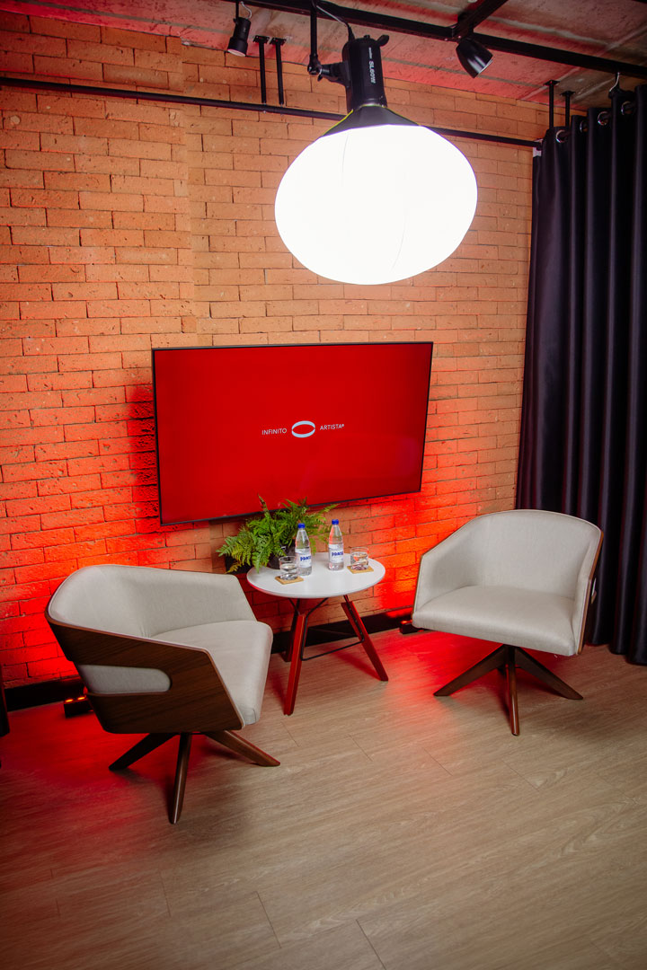 Área de entrevista com poltronas e parede de tijolos aparente